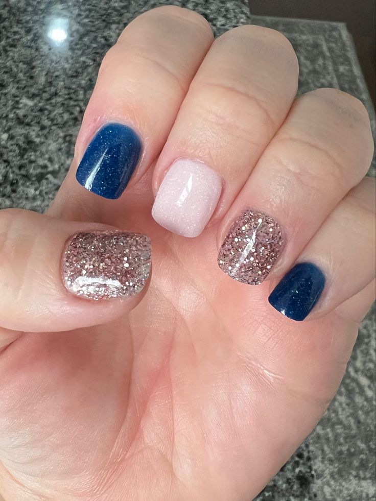 Chic and Playful Nail Design: Deep Blue, Soft Pink, and Glittery Textures.