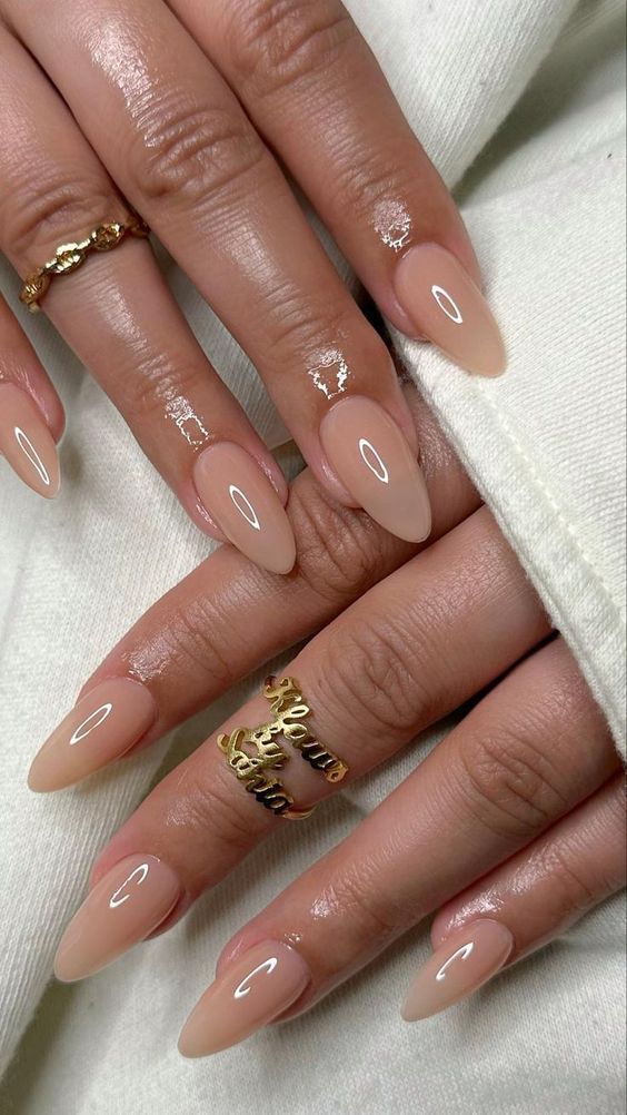 Sophisticated Almond-Shaped Nails with Soft Nude Polish and Elegant Gold Accents.