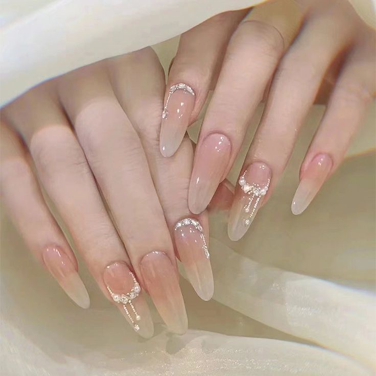 Elegant Ombre Nail Design: Long Tapered Tips with White Accents and Shimmering Embellishments.