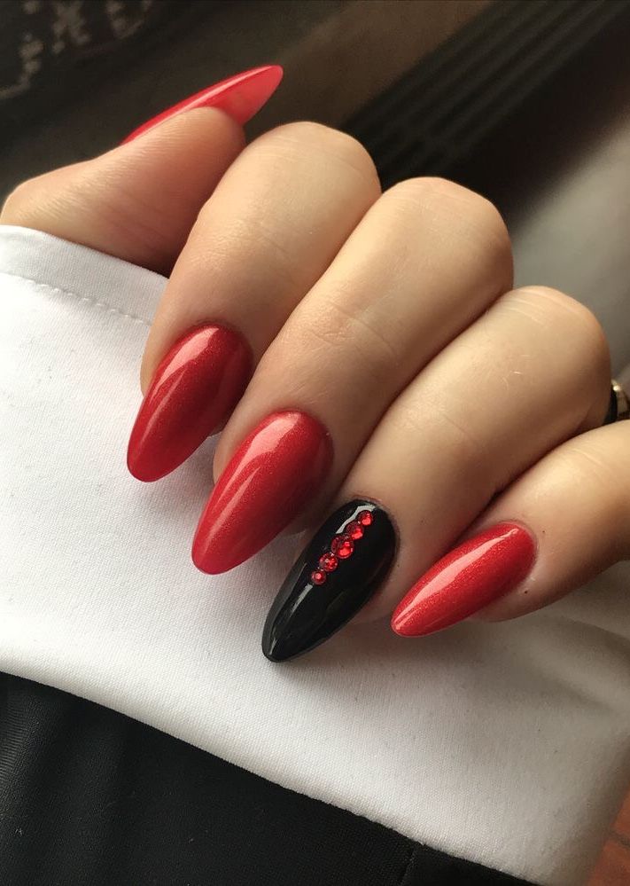 Elegant Red and Black Almond-Shaped Nail Design with Glossy Finish and Gem Accents.