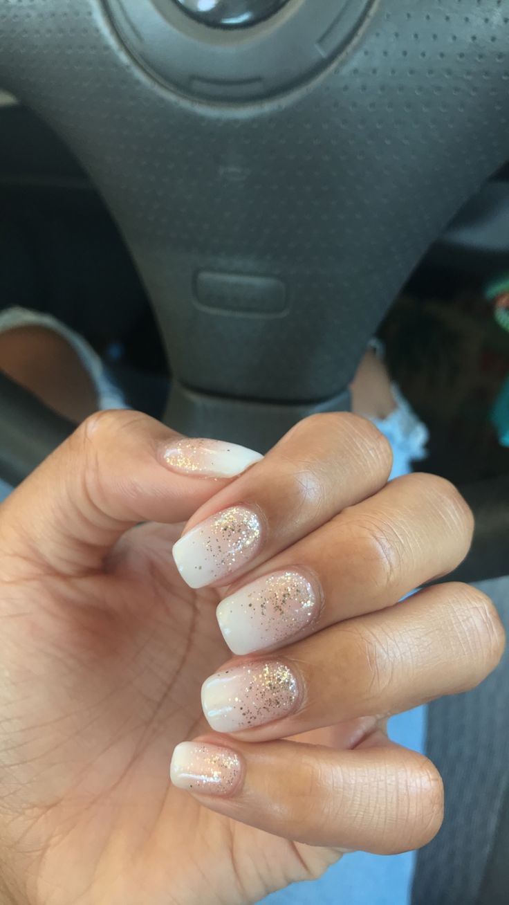 Sophisticated Ombre Nail Design with Delicate White Tips and Gold Glitter Accents.