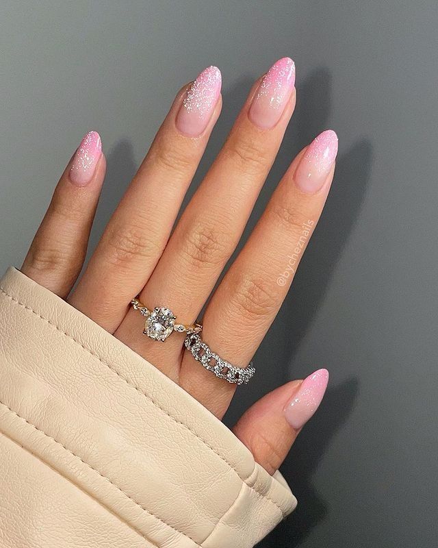 Chic Sophistication: Delicate Pink Ombre Almond Nails with Sparkling Finish and Stylish Rings