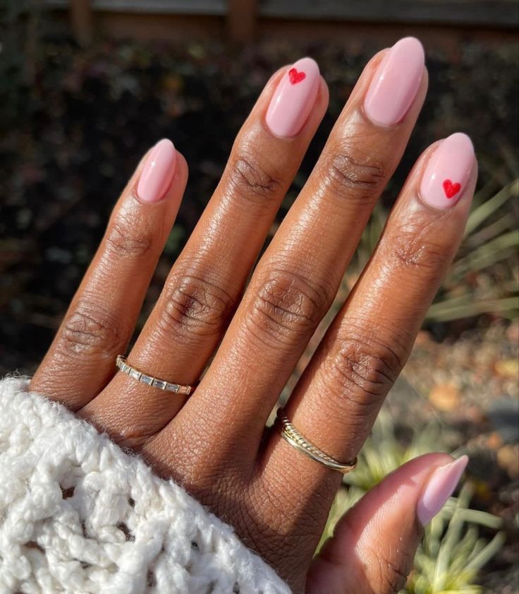 Elegant Soft Pink Nail Design with Red Heart Accents for a Playful Romantic Vibe.