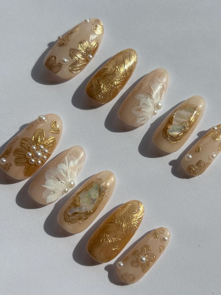 Sophisticated Gold and Nude Nail Art with Floral Patterns and Pearl Accents