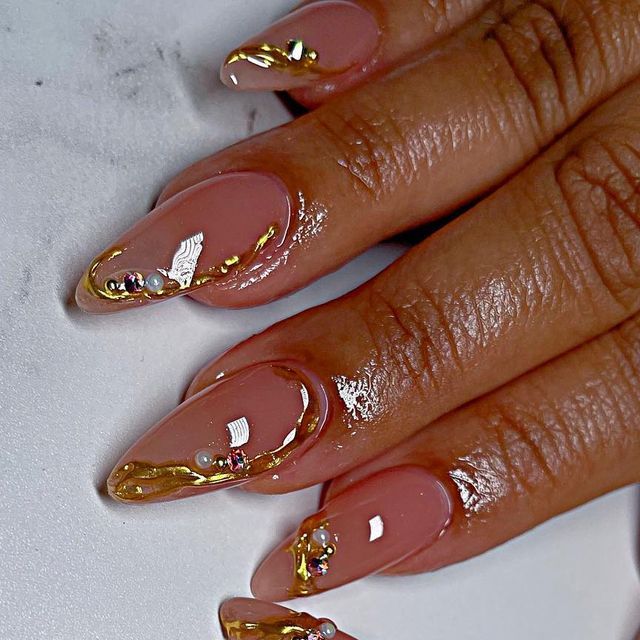 Chic Almond-Shaped Nude Nails with Gold Foil and Glamorous Gem Accents