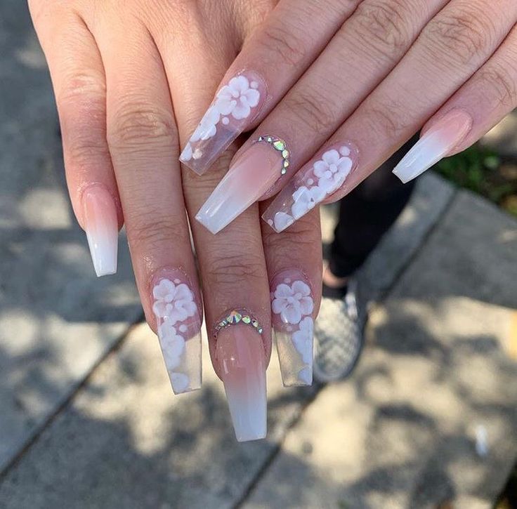 Sophisticated Nude to White Ombre Nail Design with Floral Accents and Rhinestones