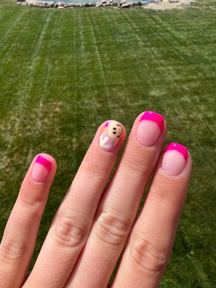 Playful Vibrant Nail Design with Bright Pink Tips and Whimsical Character Accent.