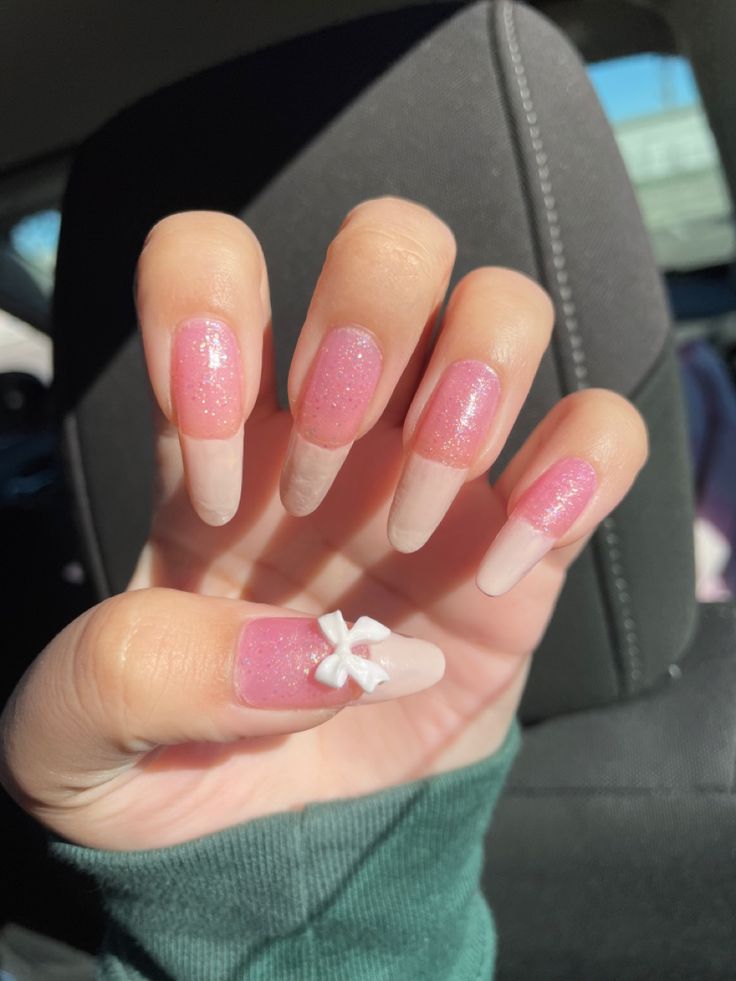 Charming Feminine Nail Design with Soft Pink, Nude Shades, and Glittery Bow Accents.