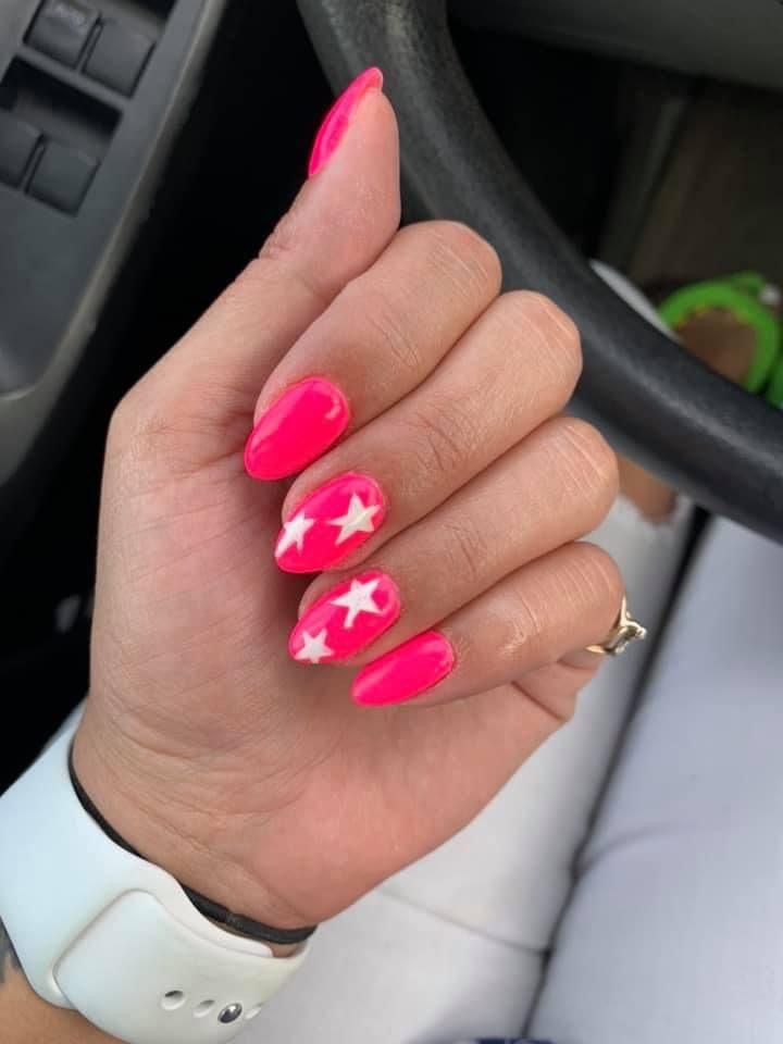 Playful Almond-Shaped Nails with Bright Pink and White Star Design for a Fun, Modern Look.