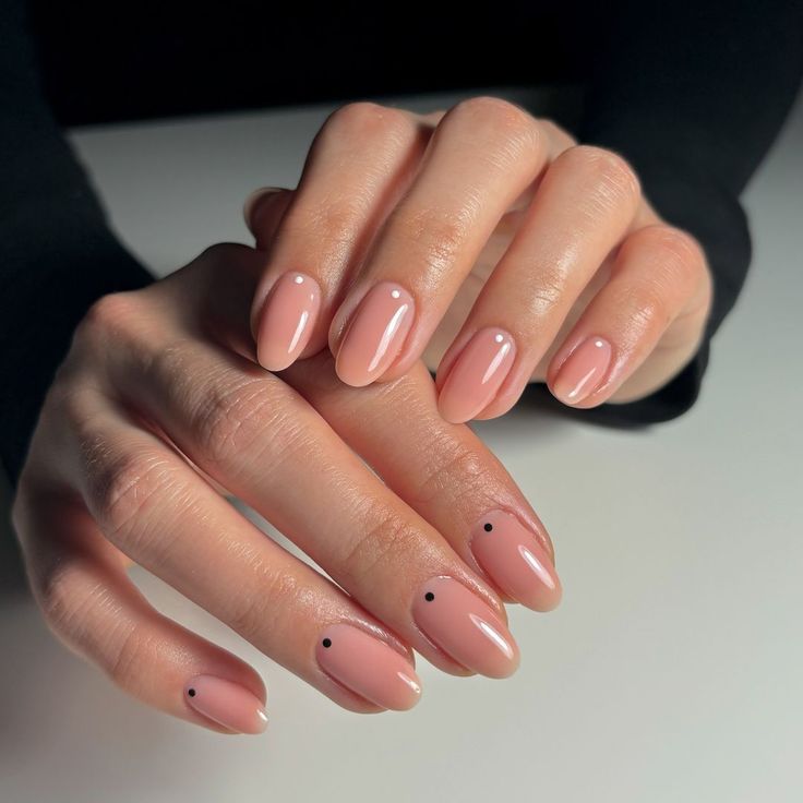 Elegant Almond-Shaped Nails with Minimalist Black Dots and Soft Nude Polish.