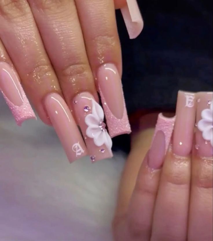 Elegant Soft Pink Nail Design with Floral Motif and Gemstone Accents.