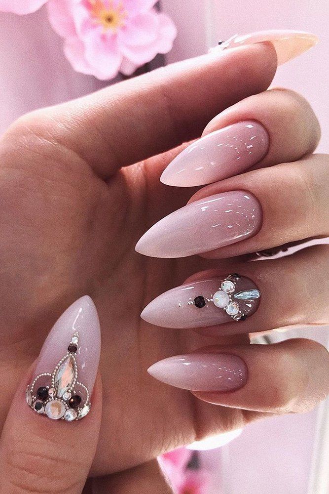 Chic Sophistication: Elegant Nude and Light Pink Nail Design with Glamorous Embellishments and Modern Oval Shape.