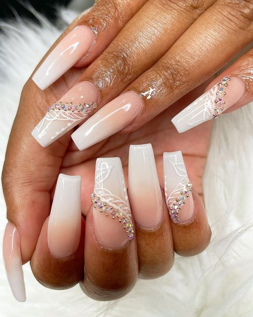 Sophisticated Almond-Shaped Ombre Nails with Lace Patterns and Rhinestone Accents.