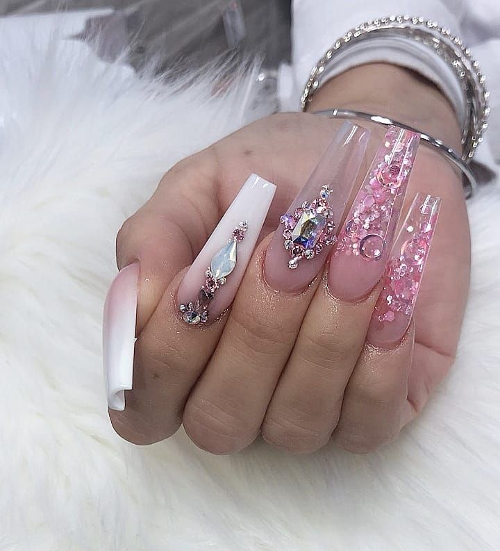 Chic Elongated Acrylic Nail Design with Clear and Pastel Pink Finishes, Sparkling Embellishments, and Elegant Ombre Accent.