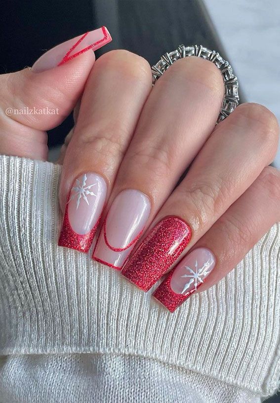 Vibrant Holiday Nail Design: Nude Base with Red Accents, Glitter, and Snowflake Details.