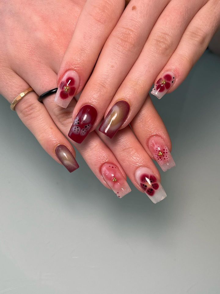 Chic Nail Art: Deep Burgundy and Pastel Gradient with Floral Accents and Gold Studs