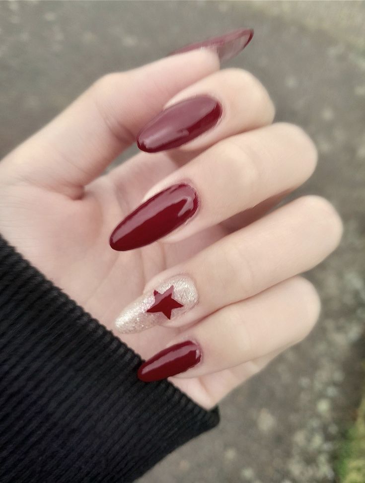 Sophisticated Red Almond-Shaped Nails with Sparkling Gold Star Accent.