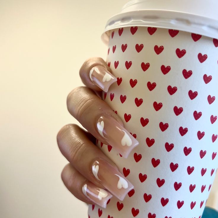 Playful Romantic Nude Nail Design with White Heart Accents and Red Heart Cup.