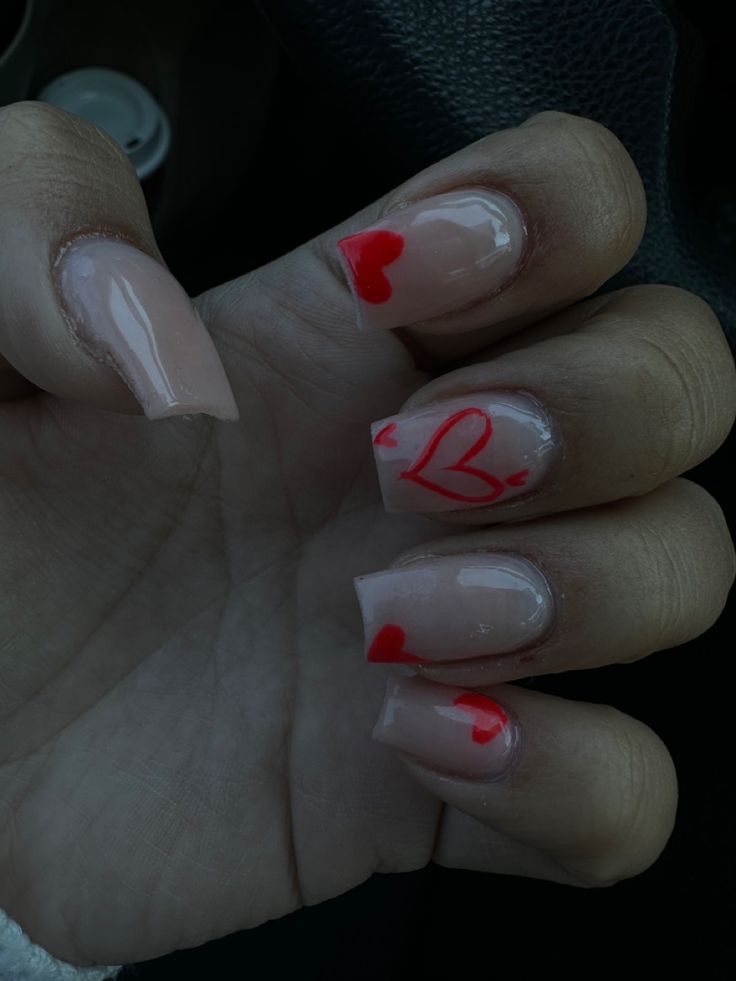 Playful Red Heart Accents on Soft Nude Base: A Whimsical Romantic Nail Design.