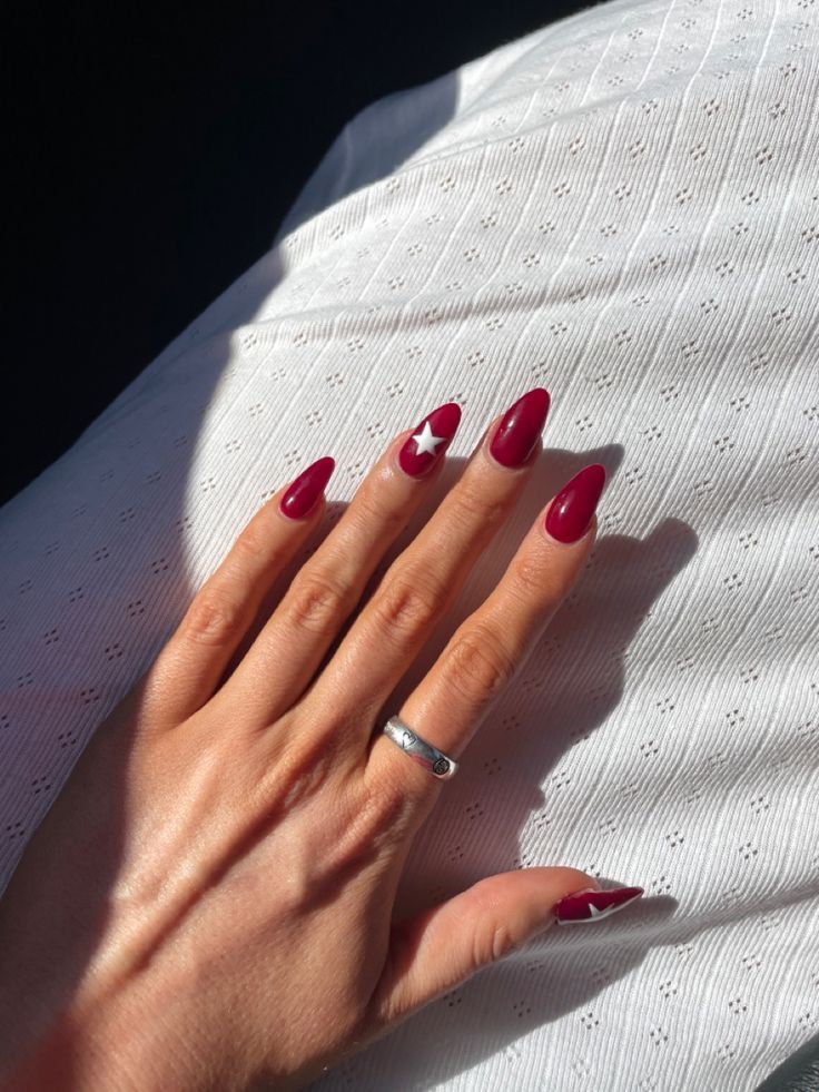 Elegant Deep Burgundy Nails with Playful White Star Accent for a Stylish Statement.