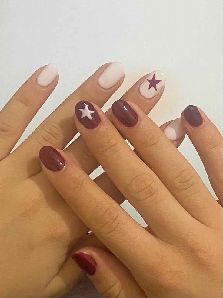 Playful Nail Design with Deep Burgundy and Soft White Star Motifs.