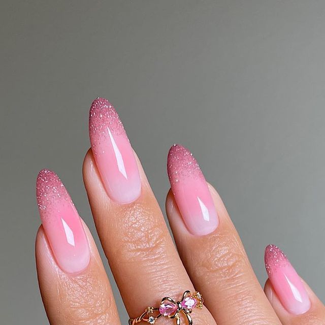 Elegant Ombre Pink Nails with Sparkling Tips and Stylish Ring Accents.