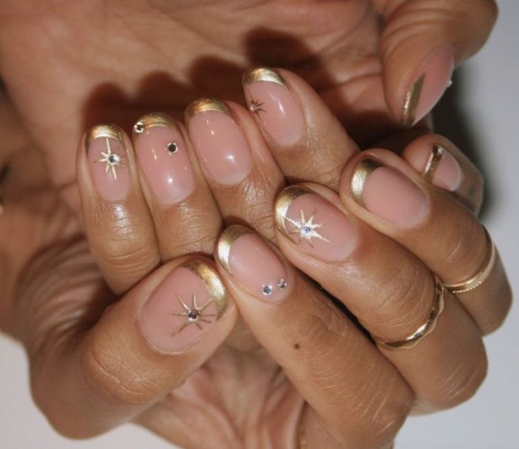 Sophisticated Nude Nail Design with Gold Accents and Star Motifs.