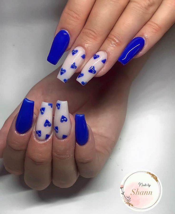 Chic Nail Design: Bold Blue and Soft Nude with Unique Patterns and Heart Accents.