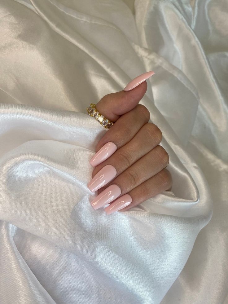 Elegant Almond-Shaped Blush Pink Nails with Glossy Finish and Gold Accessories.