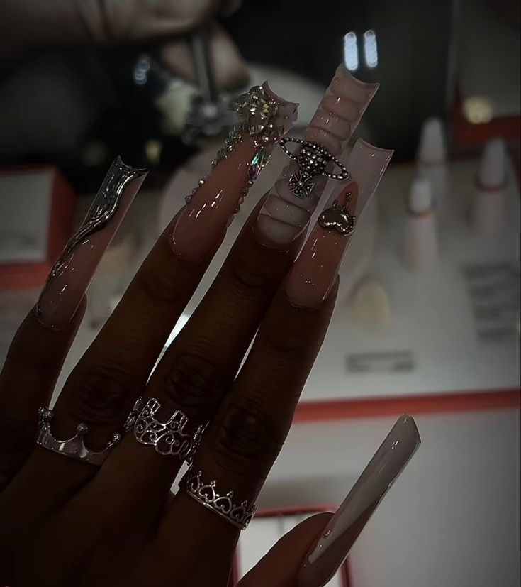 Glamorous Elegant Nail Design: Long Tapered Acrylics in Soft Nude with Intricate Embellishments.