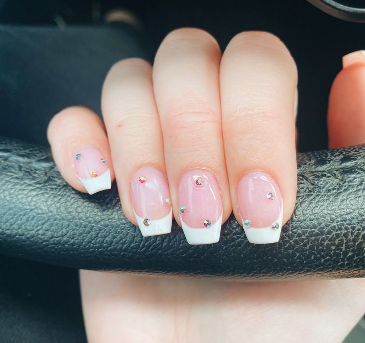 Chic French Manicure with Clear Pink Base, Defined White Tips, and Sparkling Multi-Colored Rhinestones.