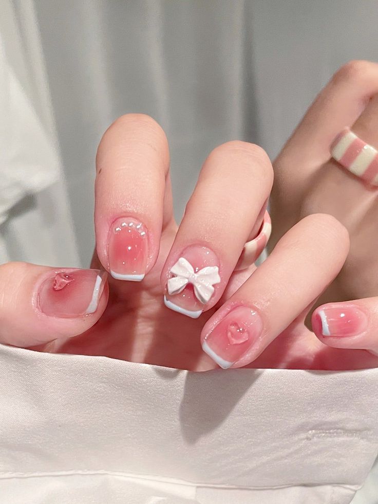 Whimsical Soft Pink Nail Design with Delicate White Tips and Playful Accents