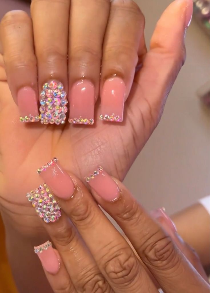 Glamorous Soft Pink Nail Design with Shimmering Rhinestones and Bold Gem Accents.