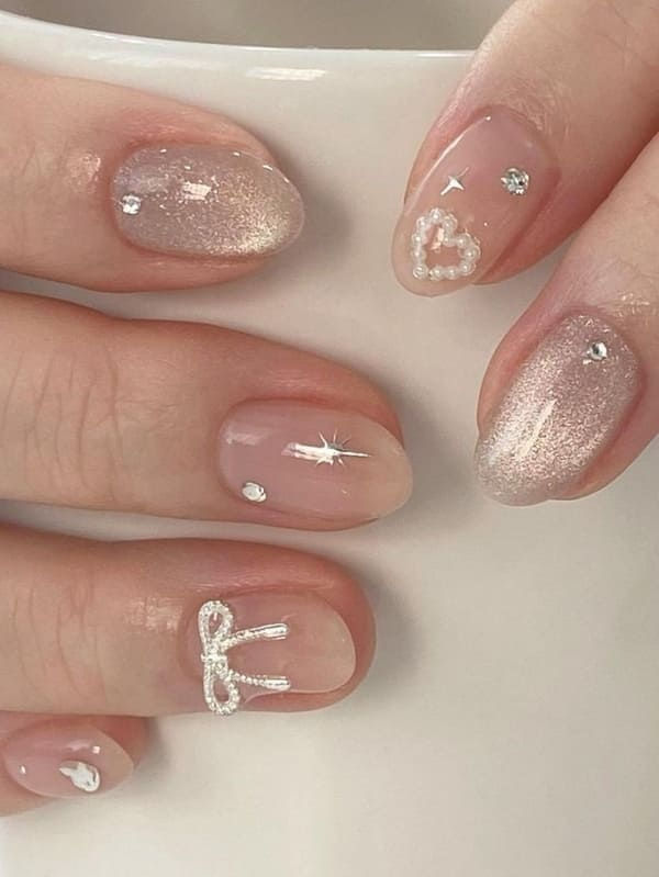 Whimsical Nude Gradient Nail Design with Delicate Embellishments.