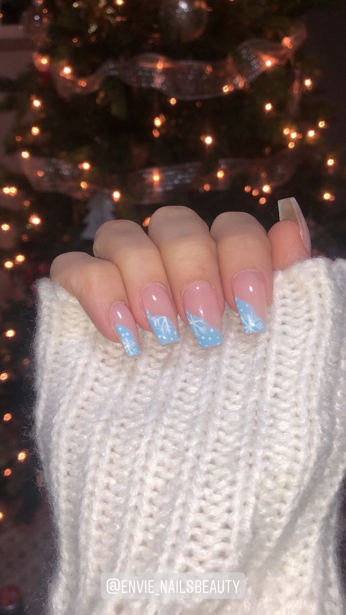 Elegant Winter Nail Design: Soft Pink Base with Light Blue Accents and White Snowflake Patterns.