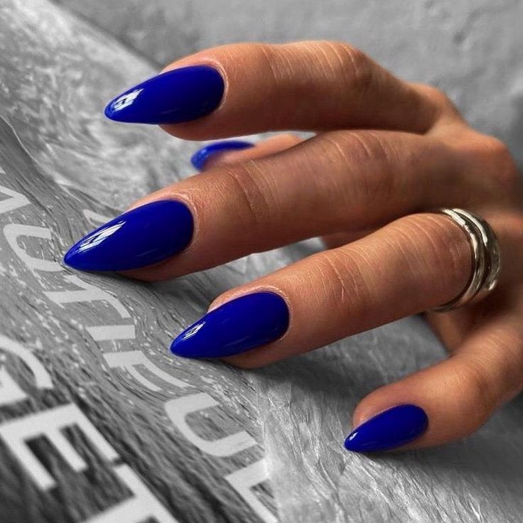 Chic Blue Almond-Shaped Nails: A Modern Elegance with Glossy Finish and Minimalist Rings.