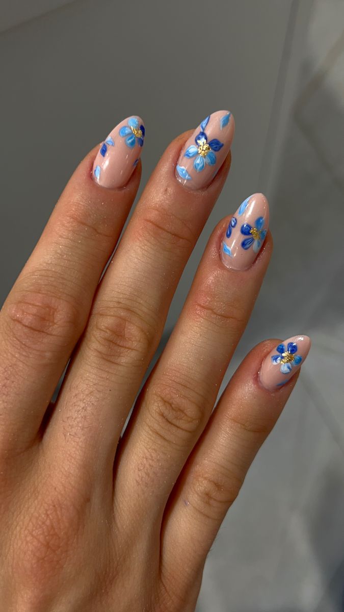 Delicate Blue Floral Nail Art on Nude Base: A Playful and Intricate Design.