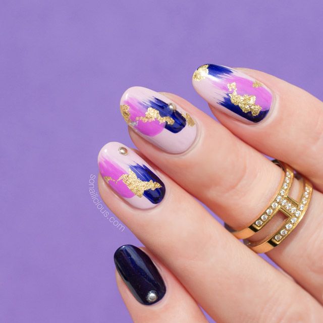 Elegant Nail Design: Deep Navy and Pastel Blend with Gold Accents and Gemstone Embellishments.