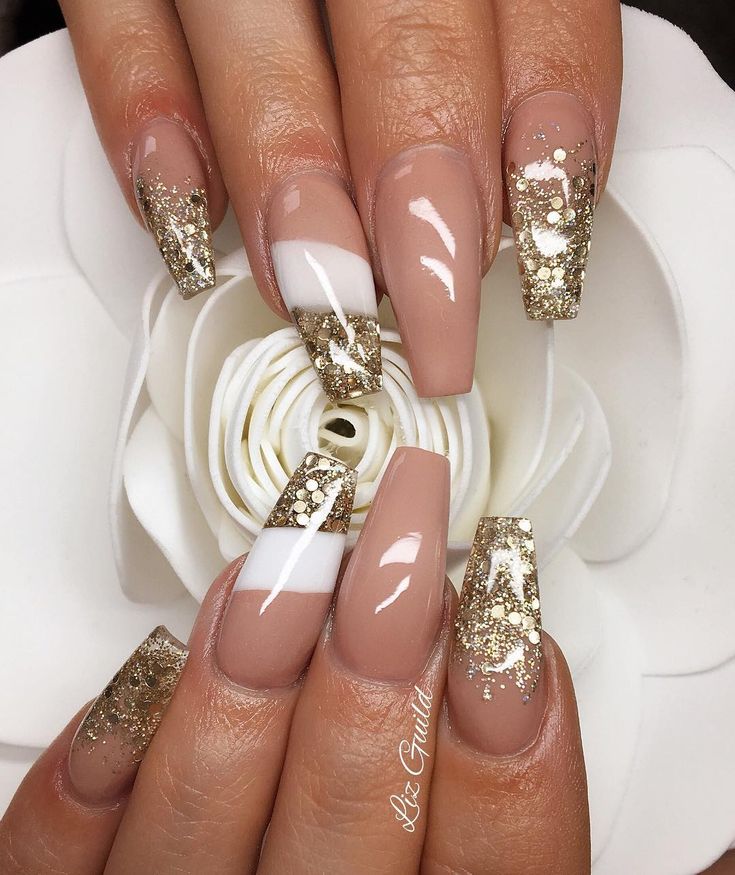 Glamorous Nude and Gold Almond Nail Design with Glittery Tips and Stripes.