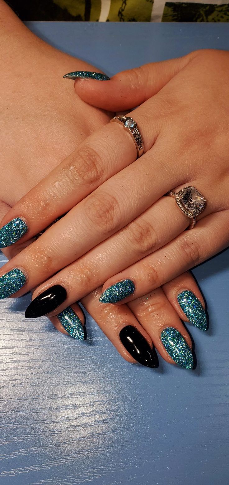 Elegant Sparkling Turquoise and Black Nail Design with Dramatic Shapes and Chic Accessories.