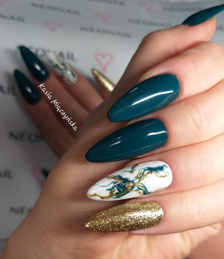 Elegant Almond Nail Design in Dark Teal and Shimmering Gold with Intricate White Accent.