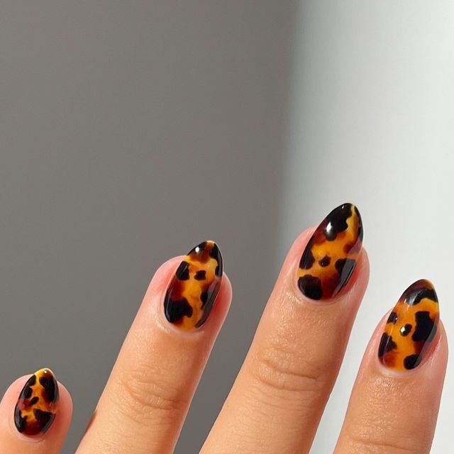 Striking Bold Tortoiseshell Nail Design: Elegant Elongated Shape in Deep Black and Warm Amber Hues.