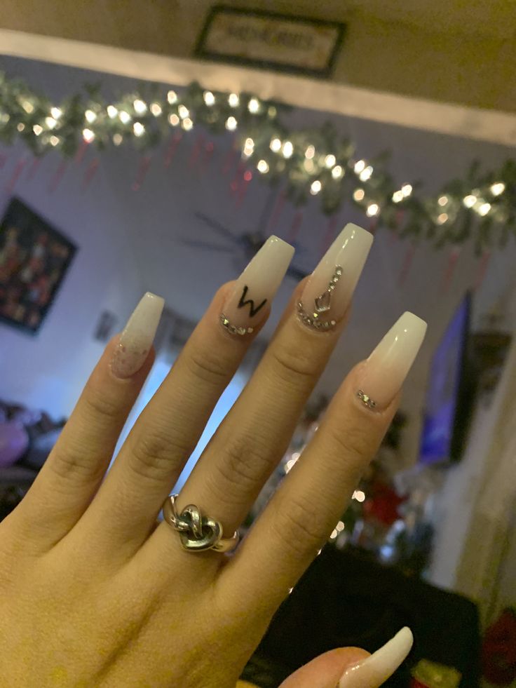 Chic Long Acrylic Nails: White and Nude Blend with Rhinestone Accents and Personalized Designs.