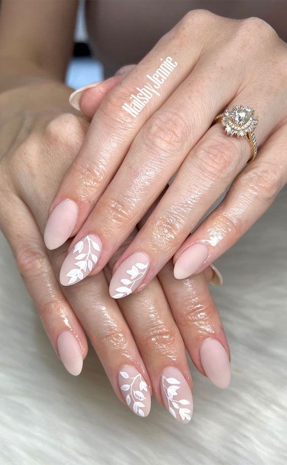 Sophisticated Elegant Nude Almond Nails with White Floral Designs and Glossy Finish