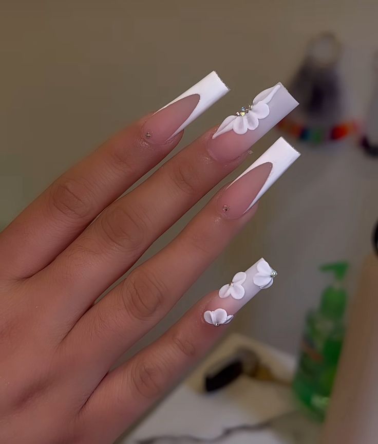 Chic White Acrylic Nails with Intricate Floral Designs and Sparkling Rhinestones