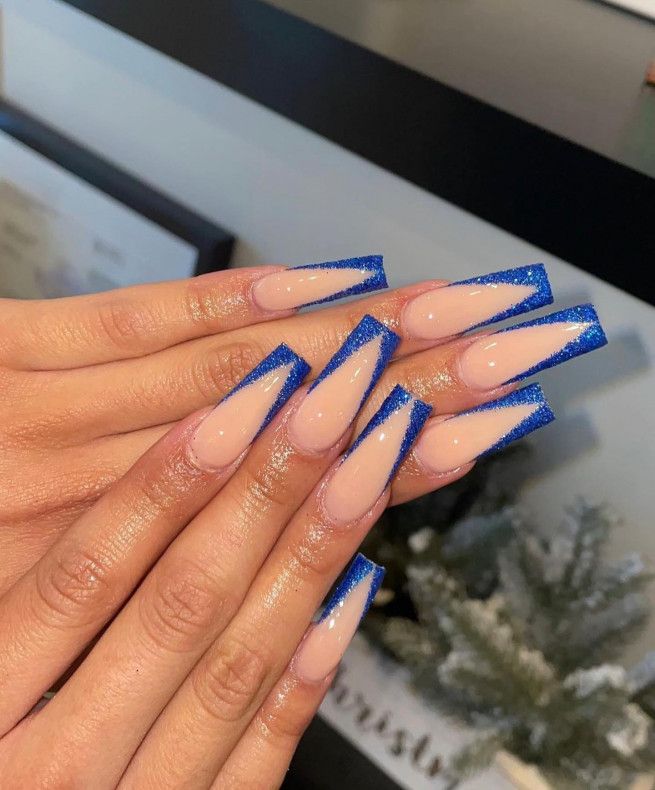 Chic Stiletto Nails: Nude Base with Striking Blue Glitter Tips for a Glamorous Look.