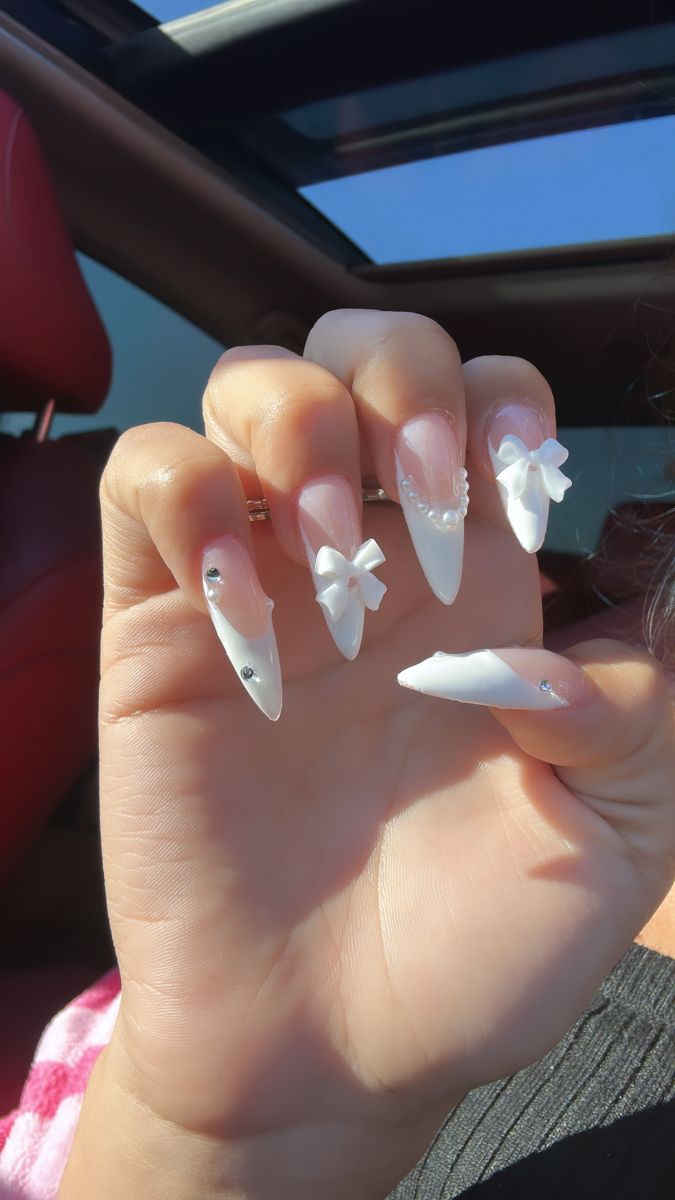 Sophisticated Stiletto Nails: White Finish with Bows and Rhinestones.