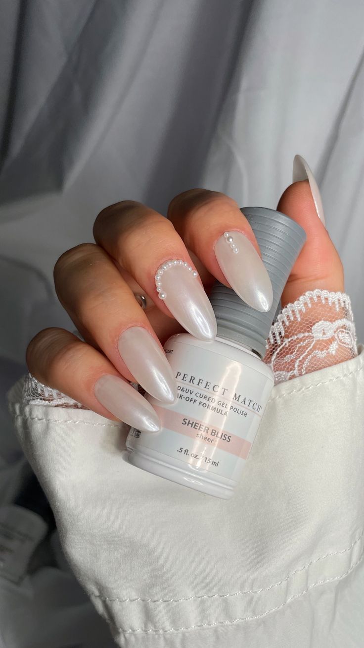 Chic Almond-Shaped Nails with Sheer White Polish and Pearl Accents for Elegant Sophistication.