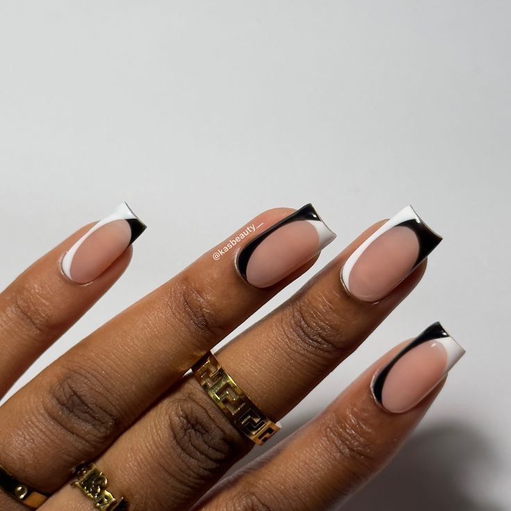 Sophisticated Nude and Black Nail Design with Chic Accents and Half-Moon Effects.