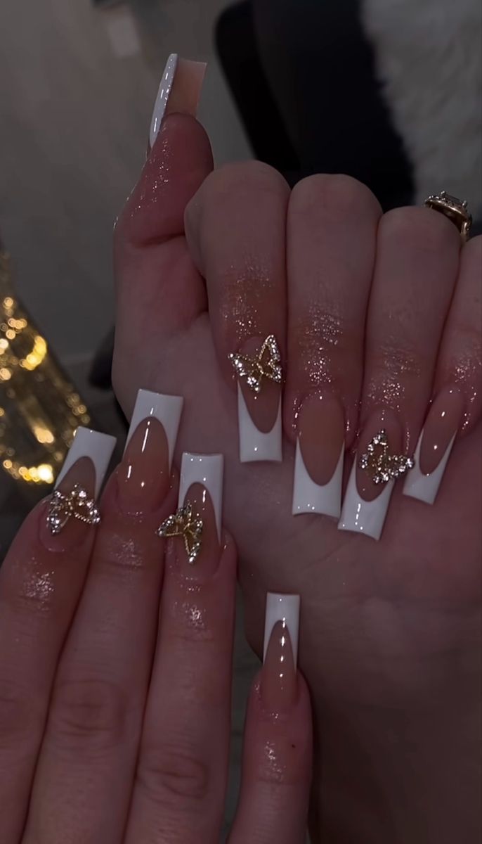 Chic Nude and White Nail Design with Gold Butterfly Accents for Glamorous Elegance.